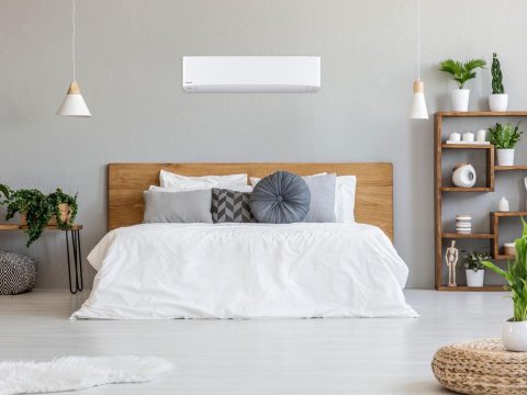 Panasonic wall-mounted heat pump above the bed in a bedroom